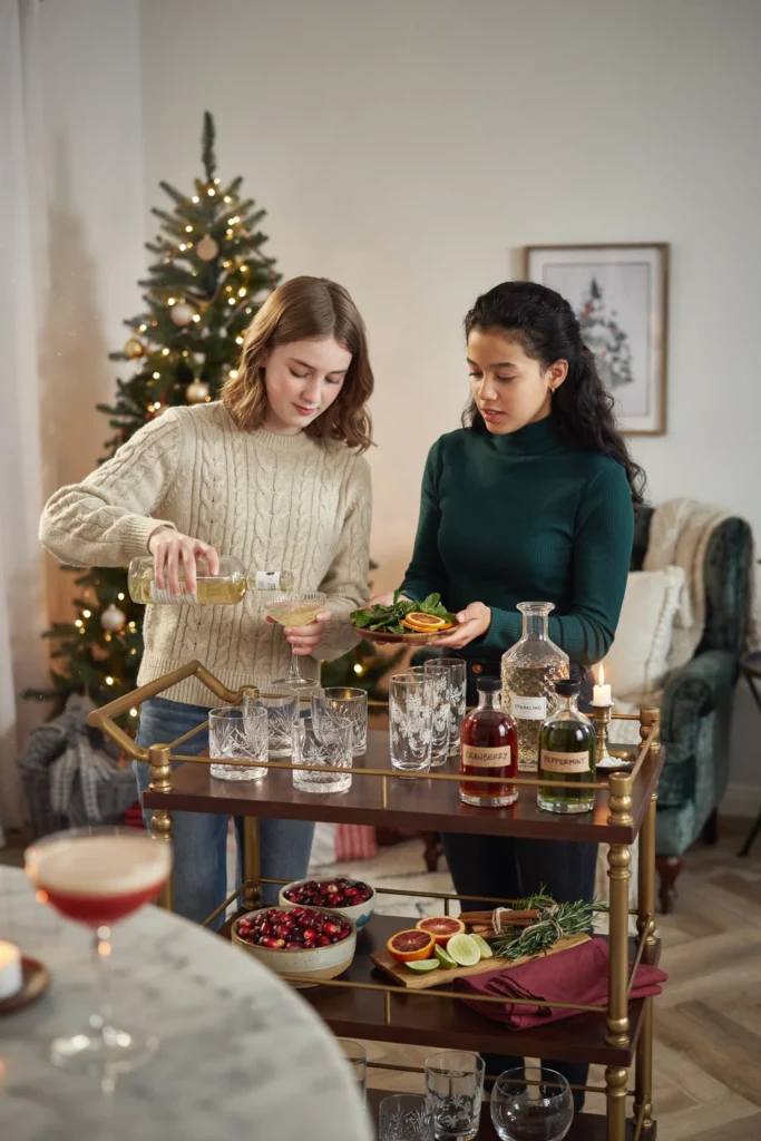 A mocktail bar with syrups, garnishes, and festive glassware at a teen Christmas party