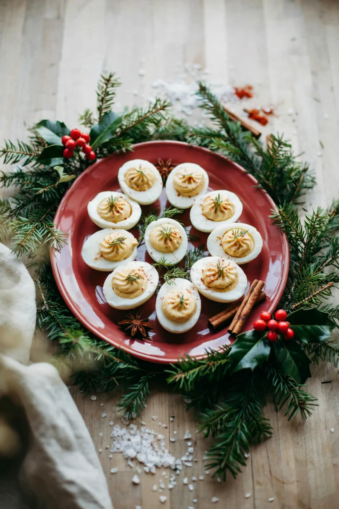 A deviled egg platter dusted with smoked paprika and fresh dill, arranged in neat rows on a red serving dish. class=