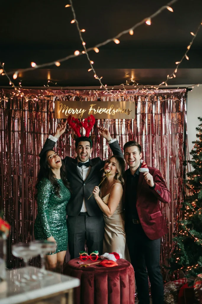 Shimmering red metallic fringe curtain photo backdrop with friends posing in front at a Friendsmas party
