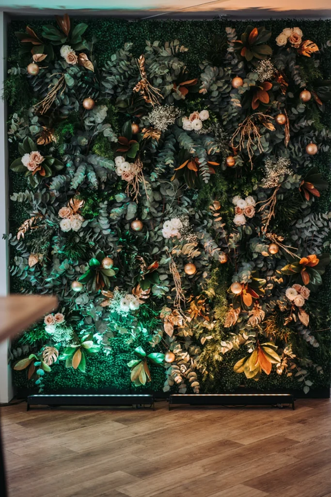 Full wall of faux greenery uplit with soft colored lighting, creating a dramatic green and gold glow