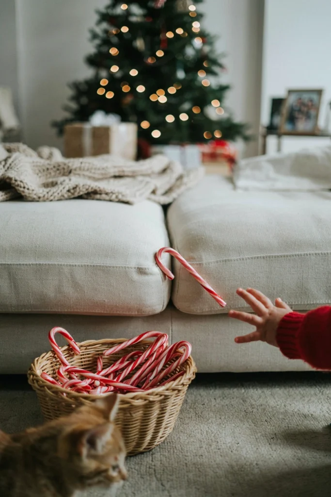 A child's hand reaching to grab a candy cane hidden among couch cushions