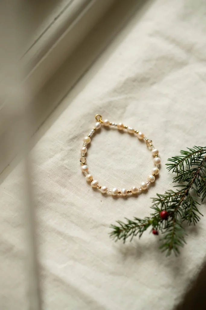 Delicate beaded ornament made from clear fishing line strung with pearl beads, gold spacers, and decorative beads creating an elegant hanging ornament
