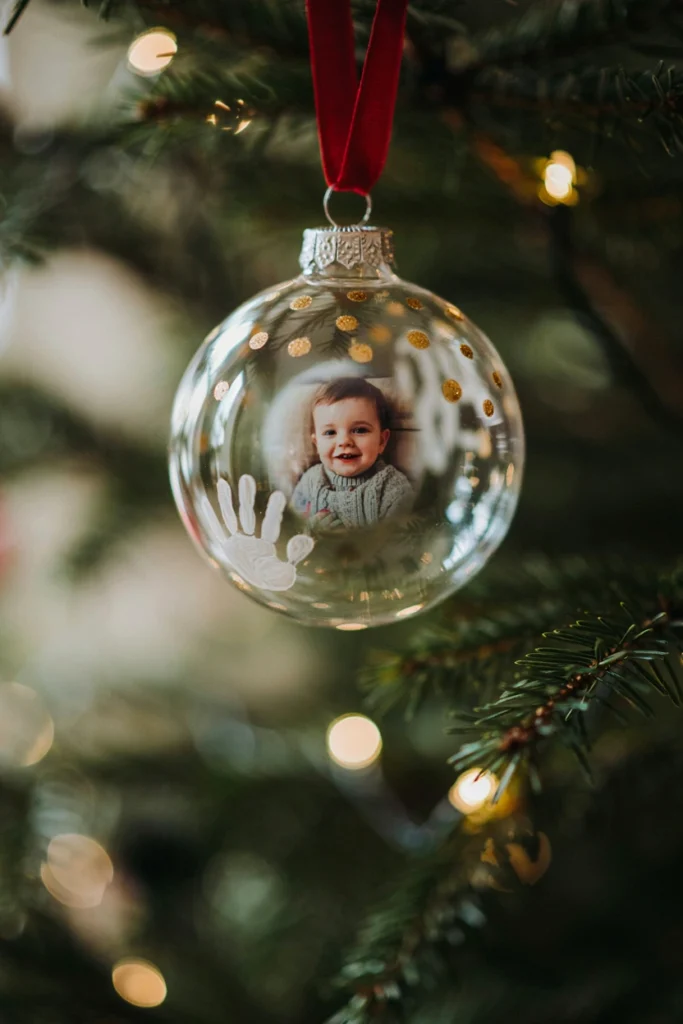 Clear plastic fillable ornament with a small photo inside, surrounded by a ring of painted handprint dots