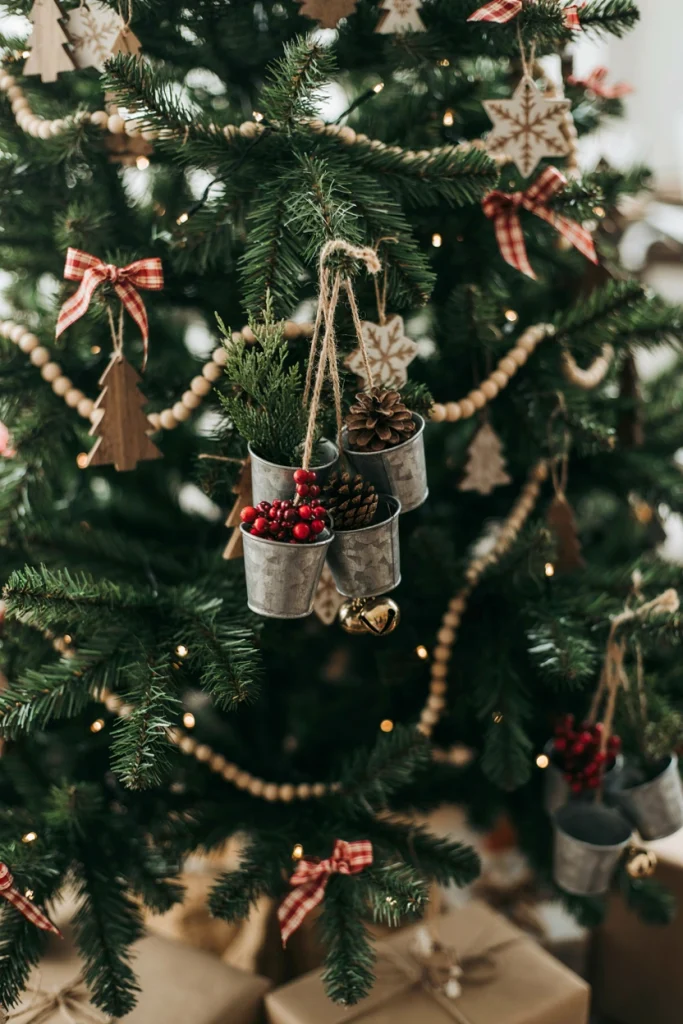 Tiny galvanized metal bucket ornaments hung on a tree, each filled with a greenery sprig