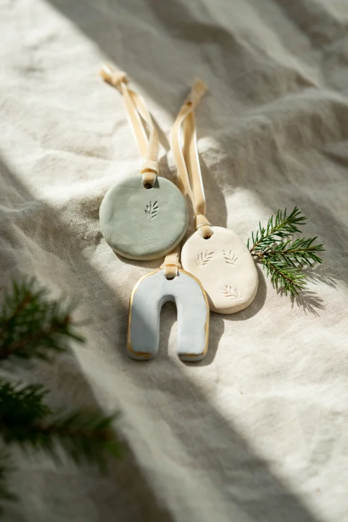 Smooth air-dry clay ornament in soft sage green with a child's thumbprint pressed into the center and the year delicately stamped in the corner