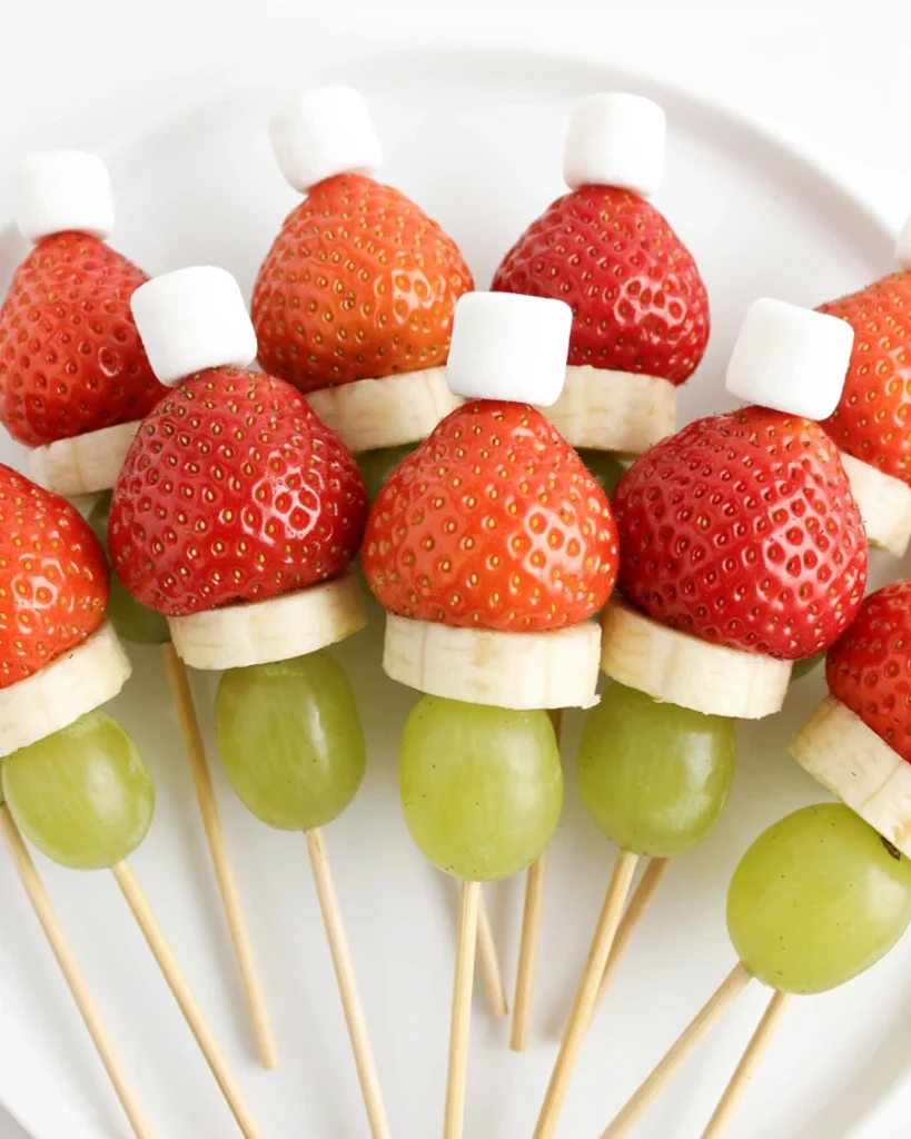 Santa hat fruit skewers made with strawberries, whipped cream, and mini marshmallows