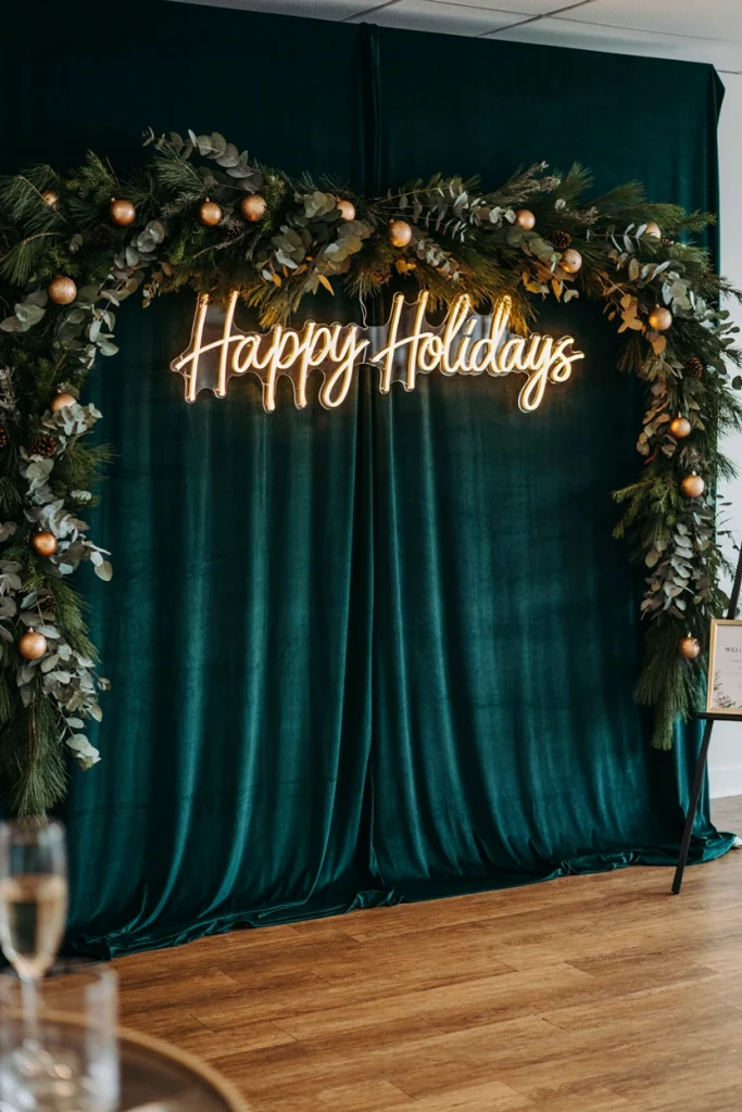 Pink and gold neon sign reading Happy Holidays mounted near a photo backdrop at a rented event space