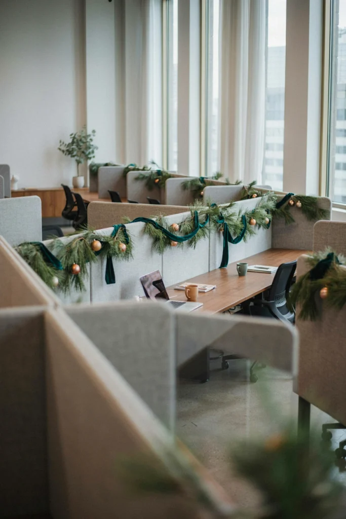 Thin pine garland with small red berries draped along the tops of office cubicle walls