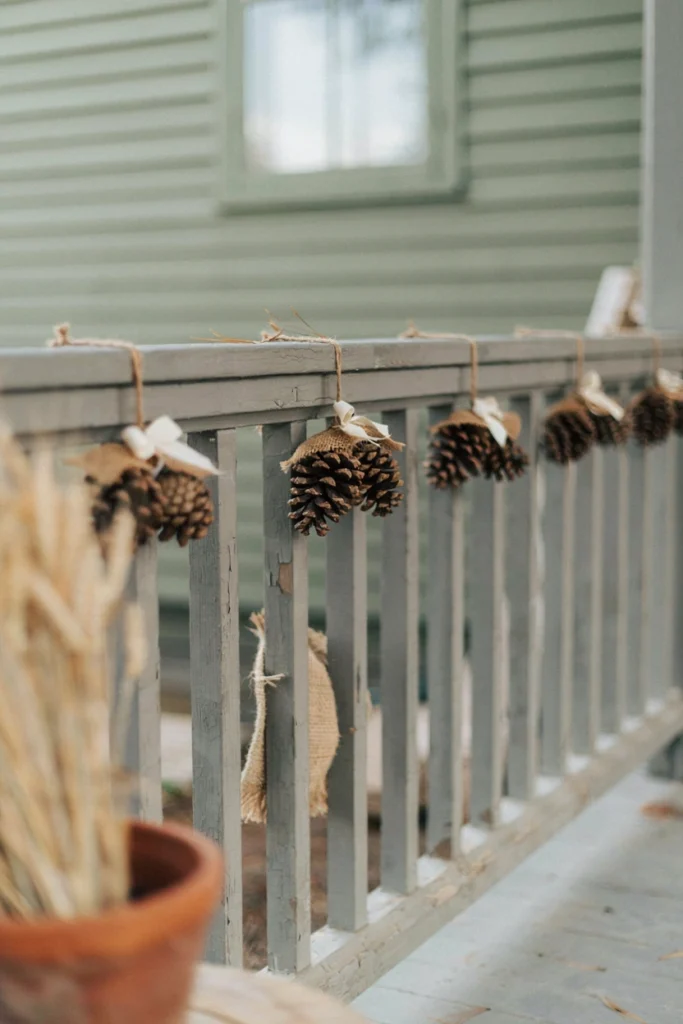 Natural pinecone bundles tied with jute twine on wooden porch railing