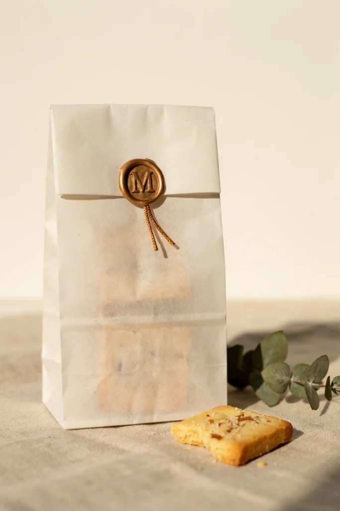 Ivory paper bag sealed with a gold wax monogram stamp and thin gold cord